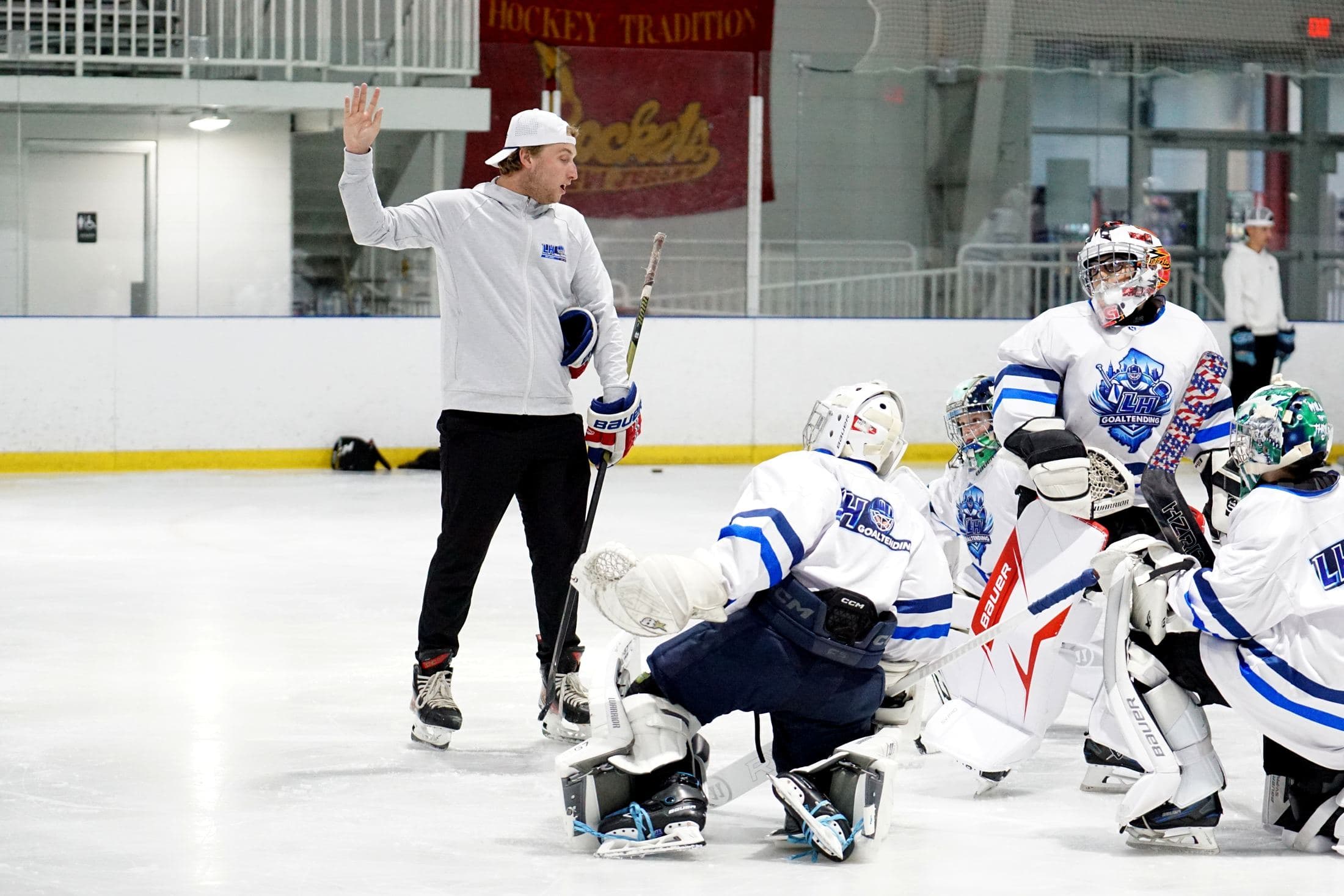 Coach Lucas Hrabkovsky walking a group of goalies through a drill on the ice