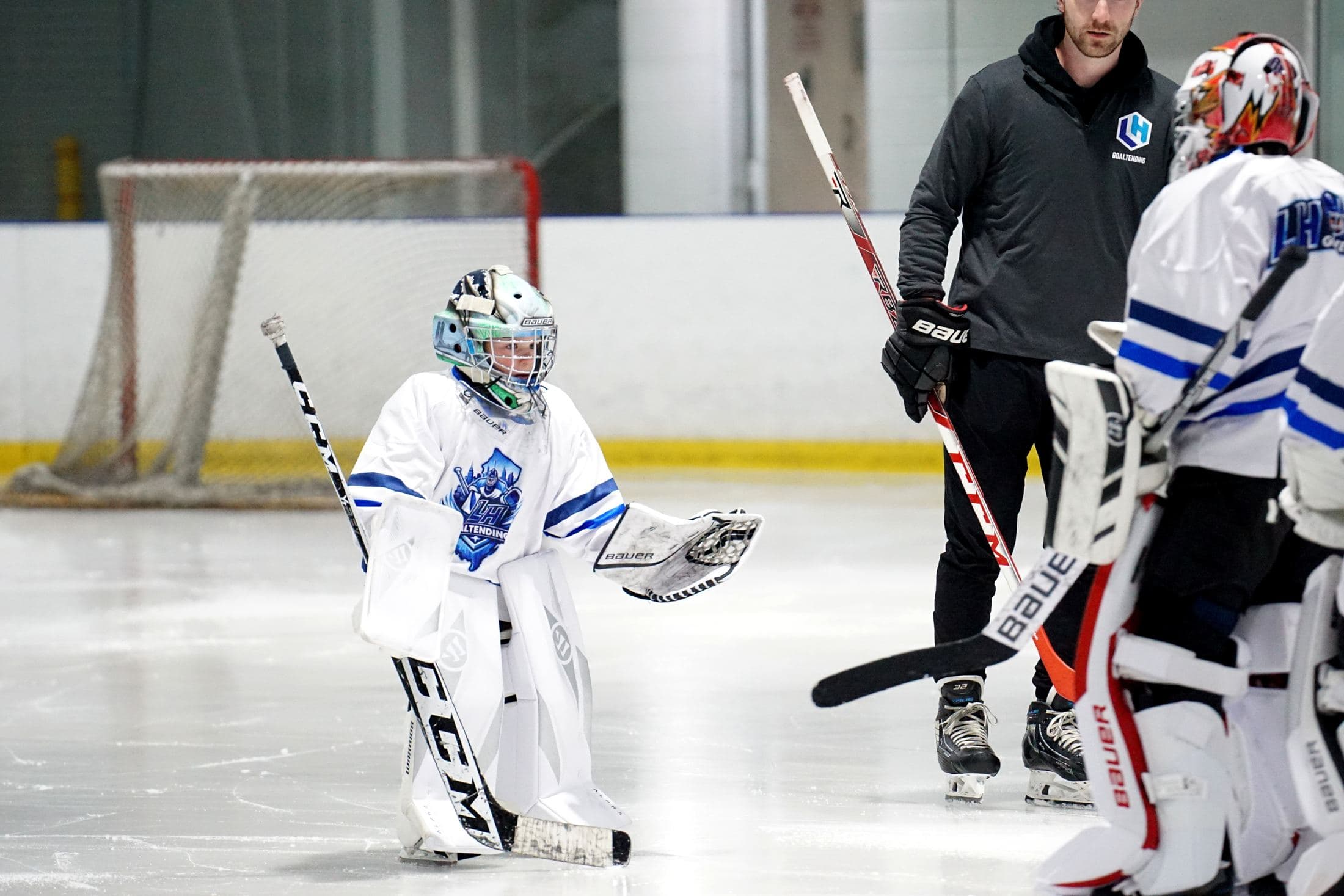 Coach Lucas Hrabkovsky working with a goalie during an on-ice session